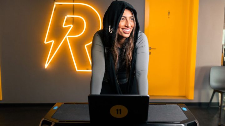 Persona entrenando en una bicicleta estática en una sala luminosa y moderna, sonriente