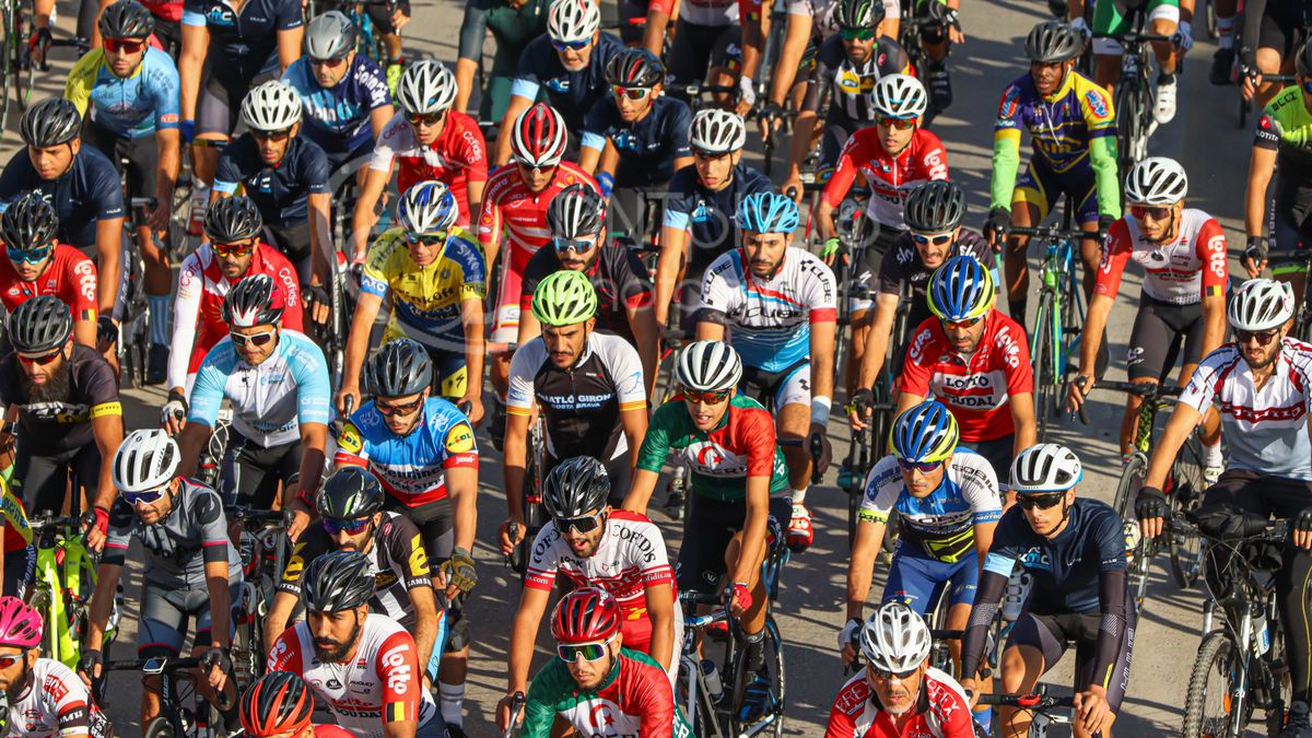 Pelotón de ciclistas con maillots de colores vivos durante una carrera por carretera
