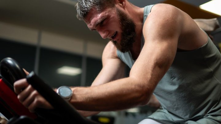 Ciclista entrenando con intensidad sobre una bicicleta estática en un gimnasio